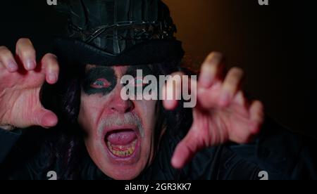 Sinistre homme avec horrible effrayant Halloween sorcher maquillage en costume faisant des visages essayant de faire peur Banque D'Images