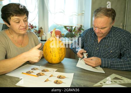 Faire de Jack O'Lantern à la maison. Processus de création d'un modèle de thème Jack O'Lantern. Un homme et une femme préparent une citrouille pour la sculpture. Banque D'Images