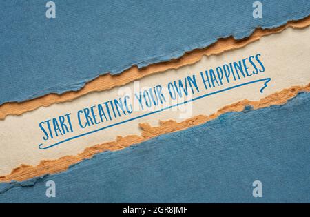 commencez à créer votre propre bonheur, l'écriture inspirante sur un papier fait main, le style de vie et le concept de développement personnel Banque D'Images