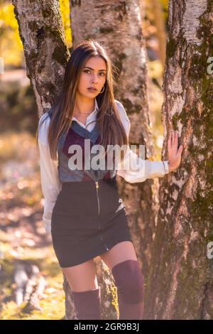 Plan vertical de l'automne, une jeune brune caucasienne dans le parc se tenant à côté de l'arbre Banque D'Images