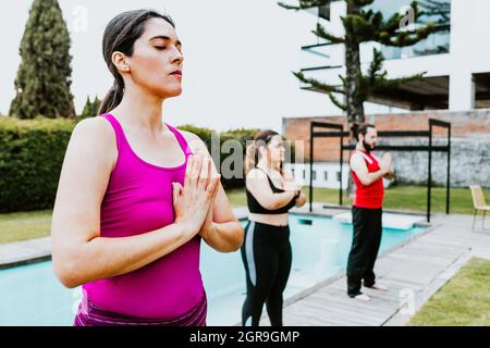 Femme hispanique d'âge moyen debout méditant avec les yeux fermés dans la session de yoga de groupe en Amérique latine Banque D'Images