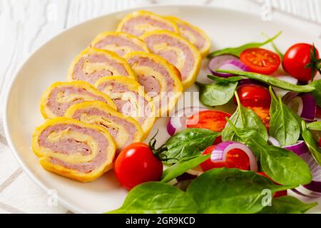petits-déjeuners au jambon et au fromage hachés avec omelettes et salade d'oignons rouges aux épinards frais sur une assiette sur une table en bois blanc, vue horizontale depuis un Banque D'Images
