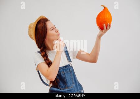 La jeune femme tenant une citrouille vérifie la qualité de la maturité. Banque D'Images