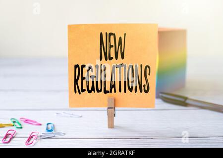 Signature manuscrite Nouvelle réglementation. Idée d'affaires réglementation contrôlant l'activité habituellement utilisée par les règles. Bloc de pinces à linge de note autocollante vierge de Banque D'Images