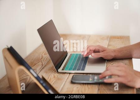 Gros plan des mains d'un homme tapant sur un clavier, à la recherche d'informations. Un rédacteur pigiste travaille sur un projet. Le concept de travail à distance. Photo de haute qualité Banque D'Images