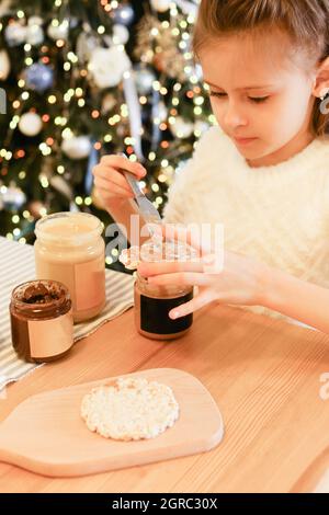 Une jeune fille mange du beurre d'arachide sur fond de Noël Banque D'Images