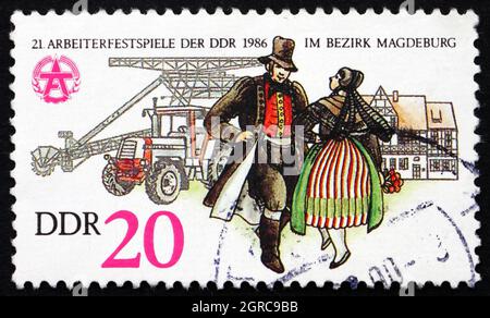 RDA - VERS 1986 : un timbre imprimé en RDA montre couple dans la tenue folklorique, Construction de maison, 21e Jeux des travailleurs, Magdeburg, vers 1986 Banque D'Images