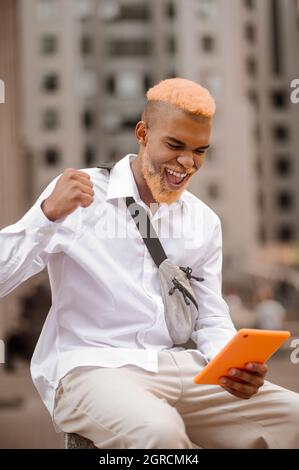 Image d'un homme aux cheveux teints avec une tablette dans les mains Banque D'Images