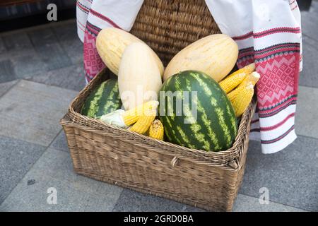 Pastèques, melons, épis de maïs dans un panier en osier avec des serviettes brodées à vendre sur le marché. Banque D'Images