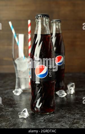 Odessa, Ukraine - 23 septembre 2021 : bouteilles Pepsi, verre avec pailles et glace sur fond de bois. Banque D'Images