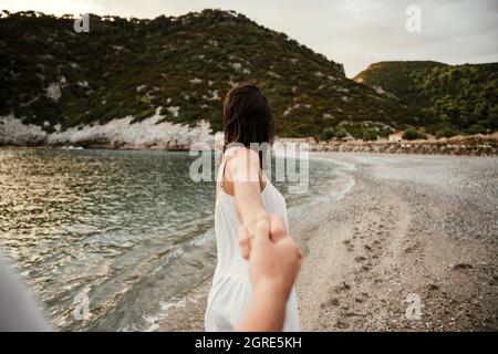 Femme caucasienne marchant le long de la plage avec un petit ami Banque D'Images