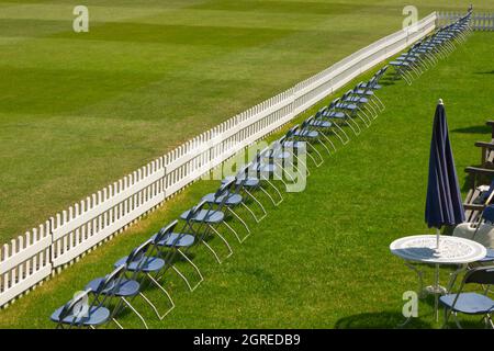 Rangée de chaises et clôture de piquetage soigneusement agenlée sur terrain de cricket Banque D'Images