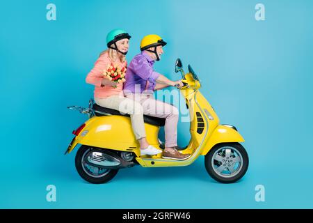 Portrait de couple gai attrayant vélo portant des fleurs ayant l'amusement isolé sur fond bleu clair de couleur Banque D'Images