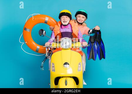 Photo de gris cheveux retraités vieux couple mariés personnes vacances bicyclette tenir caoutchouc gonflable cercle casque isolé sur fond bleu de couleur Banque D'Images