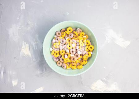 Plusieurs boucles de fruits de céréales colorées dans un bol sur fond gris. Vue de dessus, plat, espace de copie. Concept petit déjeuner Banque D'Images