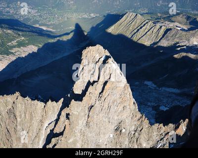 VUE AÉRIENNE. Face sud-est des Drus (3754 mètres de haut) avec son ombre projetée sur la vallée de Chamonix (1100 mètres). Haute-Savoie, France. Banque D'Images