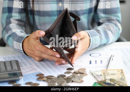 Femme montre un portefeuille vide sur les pièces de monnaie et les documents de table Banque D'Images