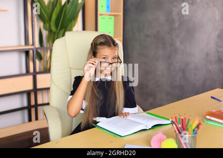 Portrait d'une fille dans un uniforme d'école avec un livre entre ses mains. L'enfant lit un manuel. Préparer une écolière pour une leçon ou un examen scolaire Banque D'Images