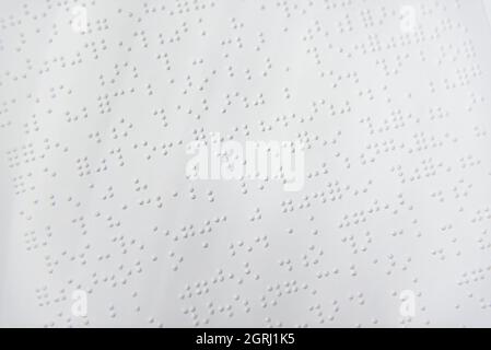 Fragment de texte en Louis Braille imprimé sur une feuille de papier standard utilisant un équipement d'impression spécial. Banque D'Images