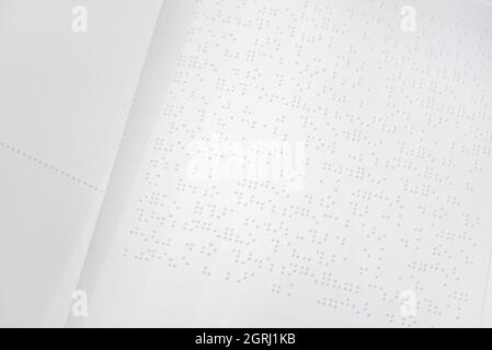 Fragment de texte en Louis Braille imprimé sur une feuille de papier standard utilisant un équipement d'impression spécial. Banque D'Images