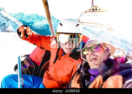 Meilleurs amis s'amusant à prendre selfie au télésiège avec équipement de snowboard sur la station de ski de montagne - Winter Friendship concept avec les jeunes Banque D'Images