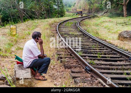 IDALGASHINNA, SRI LANKA - 16 JUILLET 2015 : un travailleur qui assure la maintenance d'une voie ferroviaire entre Idalgashinna et Haputale fait un appel. Banque D'Images