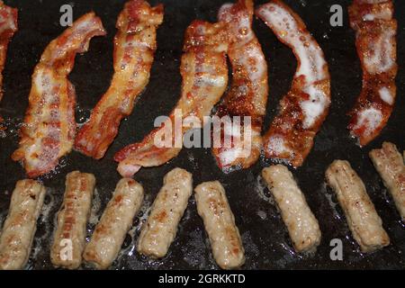 Cuisson du bacon et des saucisses sur une plaque chauffante. Banque D'Images