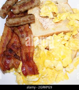 Délicieux petit déjeuner composé de bacon, saucisses, œufs et pain grillé. Banque D'Images