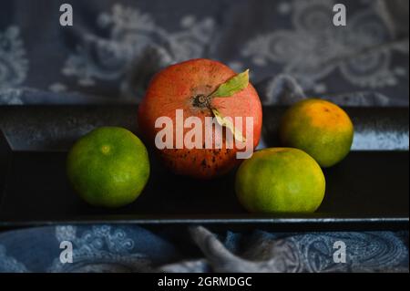 les mandarines sont couchées sur un plateau noir sur une nappe jetée inlassablement en gros plan Banque D'Images