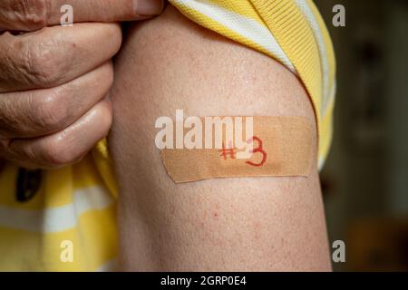 Homme caucasien senior tenant la chemise pour montrer le bandaid après le vaccin de rappel du coronavirus dans l'épaule Banque D'Images