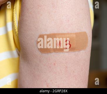 Homme caucasien senior tenant la chemise pour montrer le bandaid après le vaccin de rappel du coronavirus dans l'épaule Banque D'Images