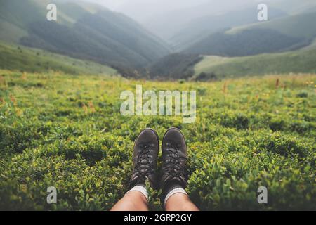 Bottes de tourisme solitaire sur la colline des montagnes couvertes de brousse de myrtille luxuriante. Photographie de paysage Banque D'Images