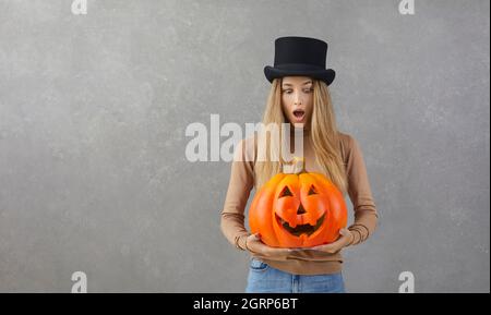 Surprise femme dans le chapeau de dessus debout sur le fond de copyspace et tenant Halloween citrouille Banque D'Images