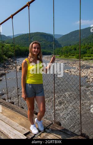 Femme se tient sur le pont suspendu au-dessus de la rivière Inguri en Géorgie Banque D'Images