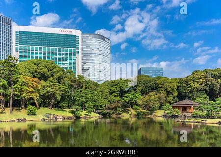 tokyo, japon - octobre 28 2021 : bâtiments Conrad et Dentsu surplombant l'étang Shiori-no-ike reflétant les pins et le chashitsu traditionnel japonais Banque D'Images