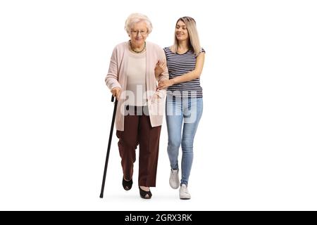 Portrait en longueur d'une jeune femme gentille aidant une femme âgée marchant avec une canne isolée sur fond blanc Banque D'Images