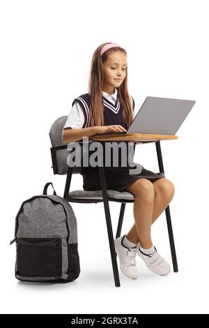 Élève assis dans une chaise de classe et travaillant sur un ordinateur portable isolé sur fond blanc Banque D'Images