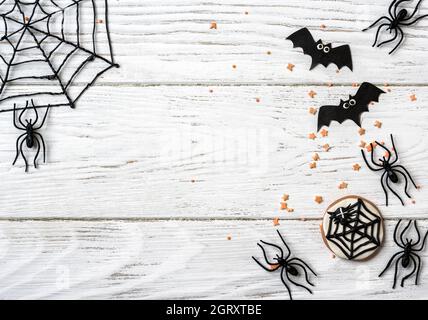 Arrière-plan d'Halloween avec biscuit, araignées et chauves-souris, vue du dessus. Objets d'Halloween sur table en bois blanc avec espace pour le texte, plat. Nourriture et Banque D'Images