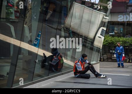 Bangkok, Thaïlande. 1er octobre 2021. Un homme portant un foulard sur son visage comme mesure préventive contre la propagation du Covid-19 est assis devant le centre commercial Siam Centre tout en utilisant son téléphone mobile. (Photo de Peerapon Boonyakiat/SOPA Images/Sipa USA) crédit: SIPA USA/Alay Live News Banque D'Images