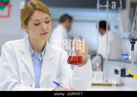 jeune scientifique féminine concentrée attrayante tenant du liquide rouge Banque D'Images