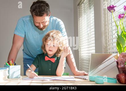 père barbu écrivant des devoirs à l'école avec son fils enfant en classe, parent Banque D'Images