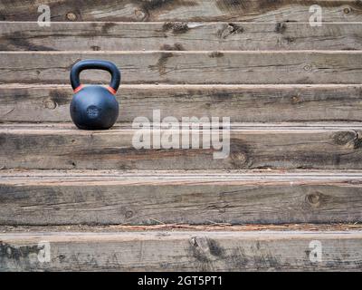 kkettlebell de compétition de fer lourd pour l'entraînement de poids sur les escaliers rustiques en bois, concept de fitness en extérieur Banque D'Images