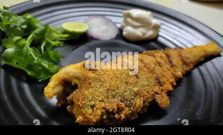 Frites de poisson entier servies sur l'assiette. Préparation indienne de style malabar décorée avec de la coriandre, de l'oignon. Repas riche en protéines. Gros plan. Banque D'Images