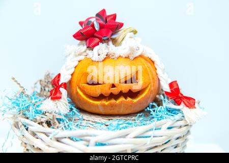 Citrouille amusante avec des tresses et un noeud dans un panier. Lanterne de Jack. Halloween insolite, humour. Banque D'Images