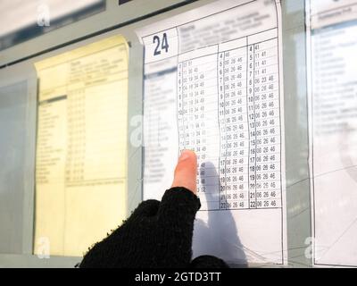 Homme vérifiant l'horaire du bus ou du tramway en pointant son doigt sur le tableau des heures de départ à l'arrivée. Transports en commun, transports en ville, transports en commun Banque D'Images