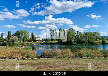 Panorama d'automne d'une partie du quartier au bord du lac avec arbres verts, arbustes et herbe brûlée, Drujba, Sofia, Bulgarie Banque D'Images