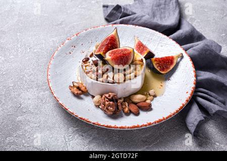 Hors-d'œuvre gastronomique au fromage brie blanc ou au camembert avec figues fraîches, noix et miel sur fond de béton gris Banque D'Images