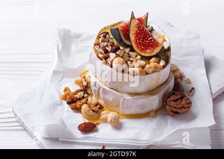 Hors-d'œuvre gastronomique de brie ou de camembert avec figues fraîches, noix et miel sur fond de bois blanc Banque D'Images