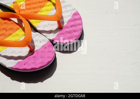 Tongs de plage colorées sur une serviette rayée. Vie d'été positive encore. Vue de dessus. Copier l'espace Banque D'Images