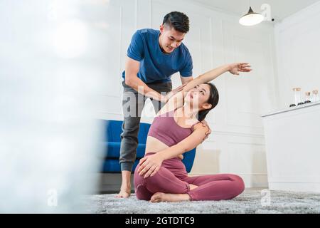 Exercices à la maison concept, asiatique Coaching Yoga hommes aider et soutenir sa petite amie quand l'exercice à la maison Banque D'Images
